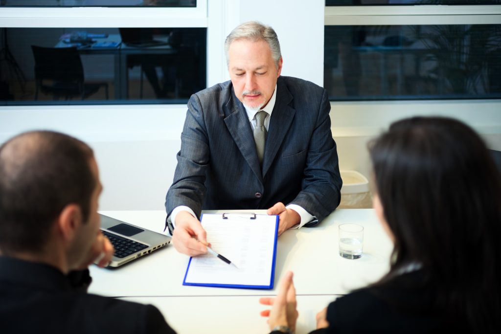 Lawyer and client shaking hands over settlement documents in modern office