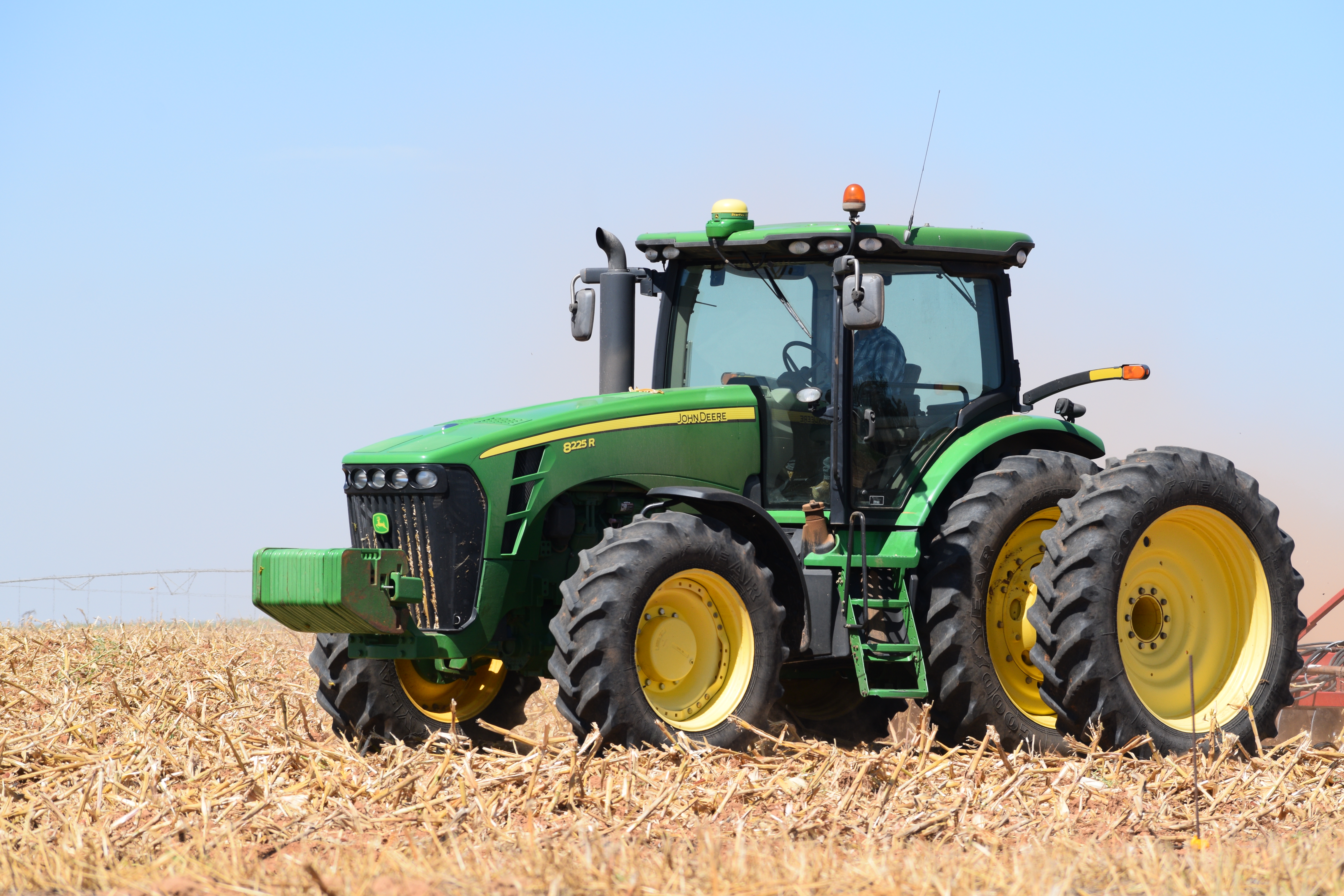 Rusted John Deere tractor in a muddy farm field with mechanic tools scattered nearby