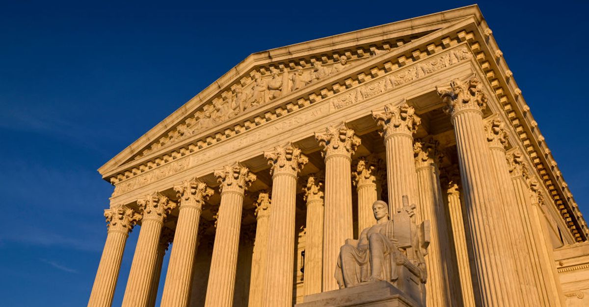 A gavel rests on legal documents near a scale of justice.