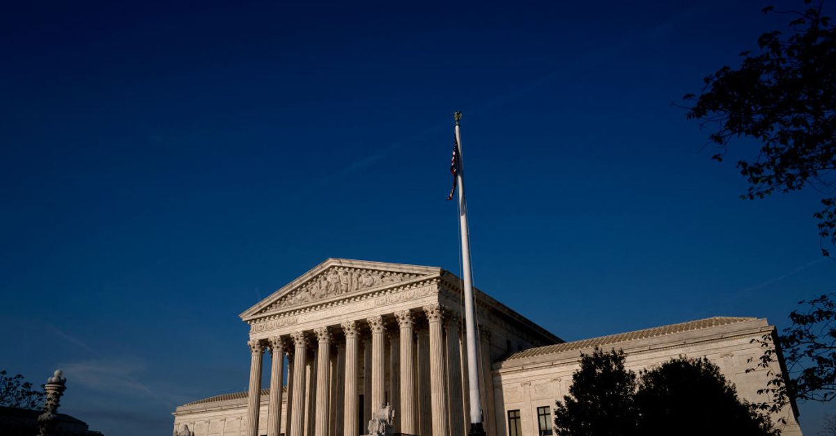 A gavel striking a sound block in front of the Supreme Court building.