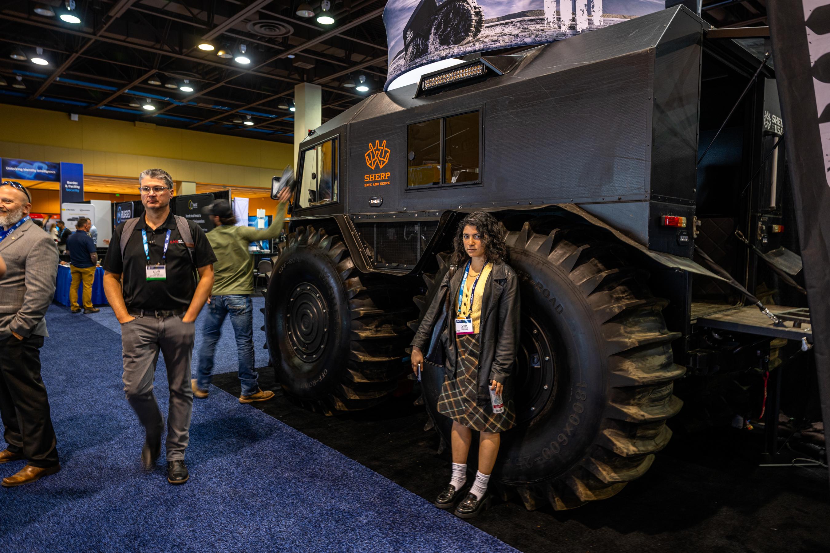 A person in a suit looking at a holographic display of data streams and maps at a technology conference, representing AI's role in border security.