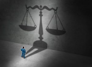 Abstract illustration of broken scales of justice with legal documents scattered around.
