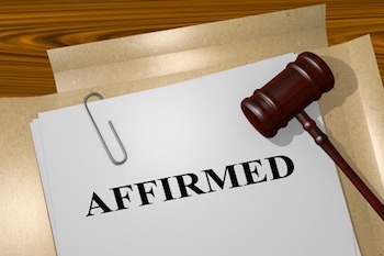 A gavel striking a block on a desk, with legal documents in the background.
