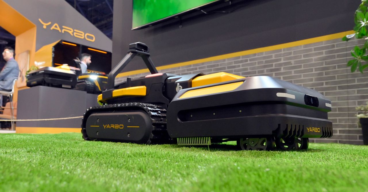 A Yarbo brand robot lawn mower shown in a suburban backyard.